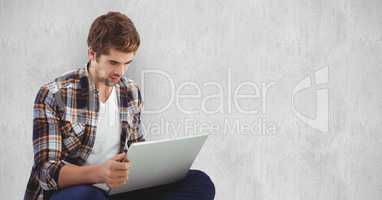 Young man using laptop against wall