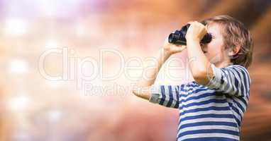 Boy looking through binoculars over blur background