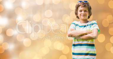 Portrait of confident boy standing arms crossed over bokeh