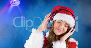Smiling woman wearing Santa hat while listening music against blue background