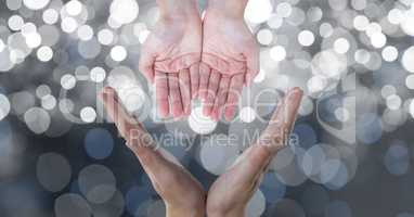 Cropped image of hands against glowing bokeh