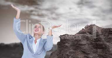 Businesswoman with arms raised by rock