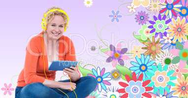 Smiling woman listening to music on headphones using tablet PC against floral background