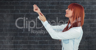Side view of redhead woman with arms raised against wall
