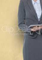Midsection of businesswoman holding digital tablet against yellow background