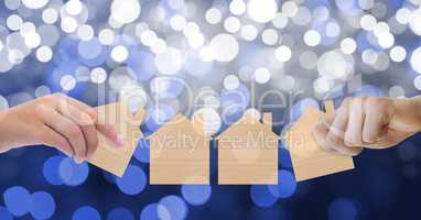 Cropped image of hands holding house paper cut outs against bokeh