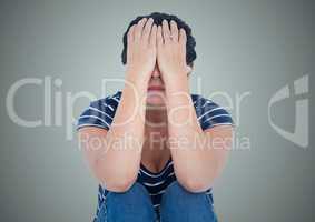 Woman sitting with hands on face against light blue background