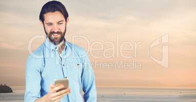 Hipster using mobile phone at beach against sky