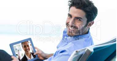 Smiling businessman video conferencing with colleague on tablet PC