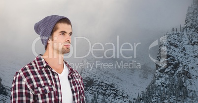 Young hipster wearing knit hat against snowcapped mountains