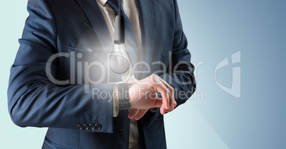 Business man mid section with glowing lightbulb over watch against blue background