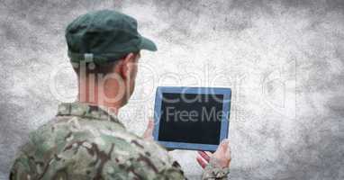 Back of soldier with tablet against white wall with grunge overlay