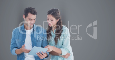 Casual male and female colleagues using tablet PC over gray background