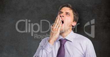 Tired businessman yawning against blackboard