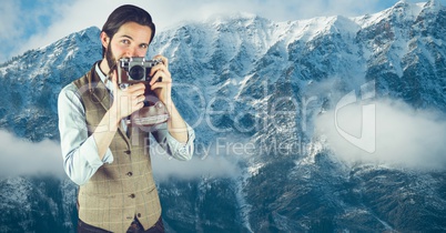 Hipster man photographing against snowcapped mountains