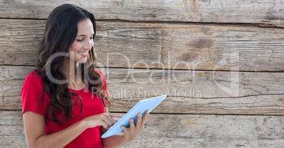 Smiling woman using tablet PC against wooden wall