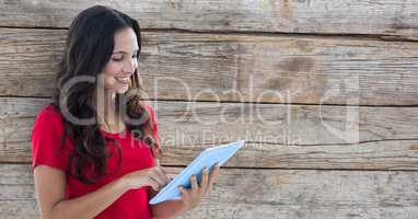 Smiling woman using tablet PC against wooden wall