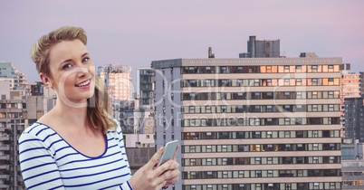 Smiling woman holding mobile phone in city