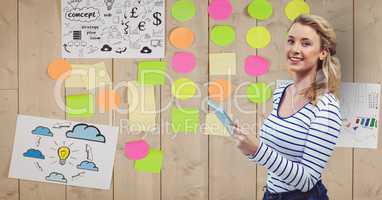 Businesswoman holding tablet PC with adhesive notes stuck on wall