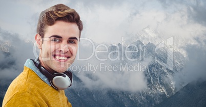 Smiling hipster with headphones against snowcapped mountains