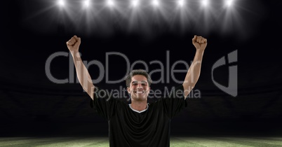 Successful soccer player with arms raised at stadium