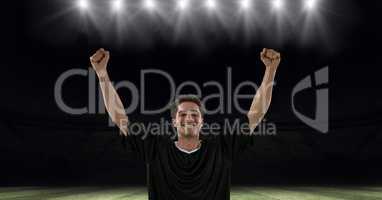 Successful soccer player with arms raised at stadium