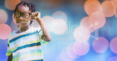 Playful boy sticking out tongue while holding eyeglasses over bokeh