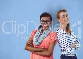 Portrait of happy businesswomen standing arms crossed against blue background