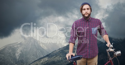Portrait of confident male traveler holding bicycle on mountain