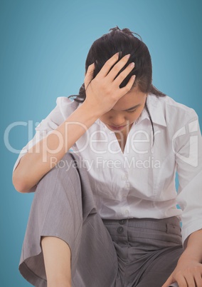 Woman sitting with hand on head against blue background