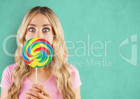 Surprised woman with lollipop candy over green background