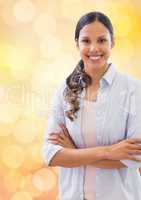 Smiling businesswoman with arms crossed over bokeh