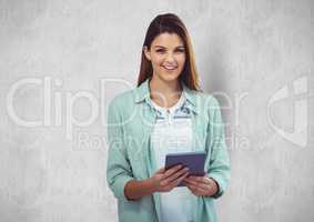 Young businesswoman holding tablet PC against wall