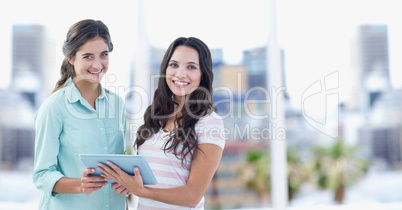 Portrait of happy female hipsters holding digital tablet in city