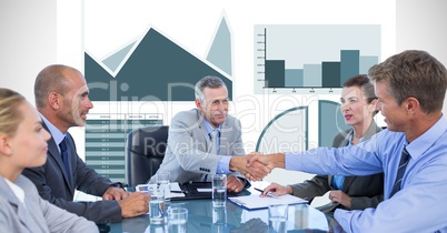 Business people shaking hands during meeting with graphs in background Business people shaking hands during meeting with graphs in background