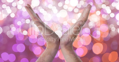 Cropped image of hands against glowing bokeh