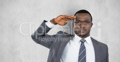 Portrait of confident businessman saluting against gray background