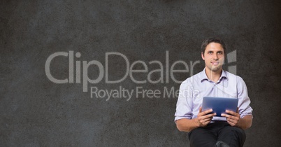 Confident businessman holding digital tablet while sitting against blackboard
