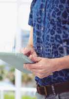 Midsection of male hipster using digital tablet against blurred background