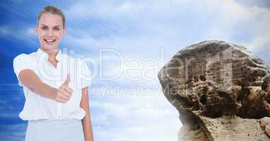 Businesswoman showing thumbs up sign by rock