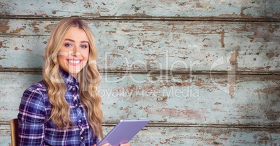 Smiling woman holding tablet PC against wall