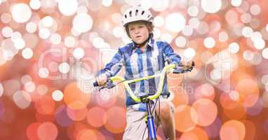 Boy riding bicycle over bokeh