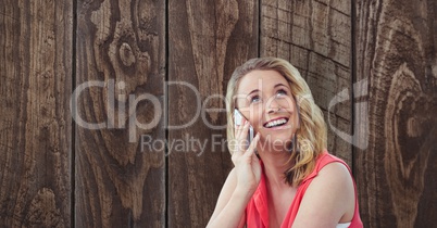 Happy woman using smart phone against wooden wall