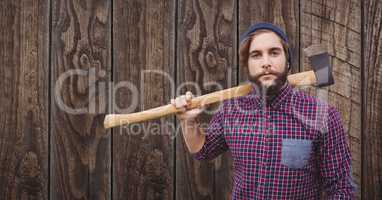 Confident hipster holding ax against wooden wall