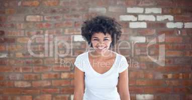 Happy woman with curly hair against brick wall