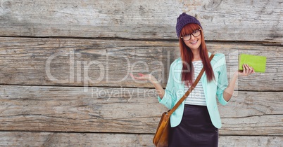 Female hipster holding clutch while gesturing against wooden wall