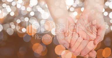 Close-up of cupped hands against glowing bokeh