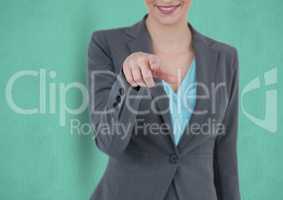 Midsection of smiling businesswoman pointing over green background