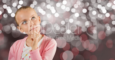Thoughtful girl with hand on chin over bokeh