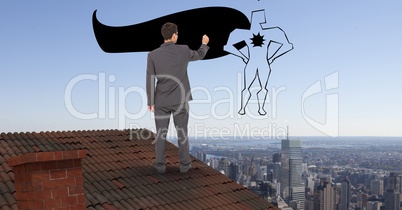 Rear view of businessman on roof drawing super hero in midair